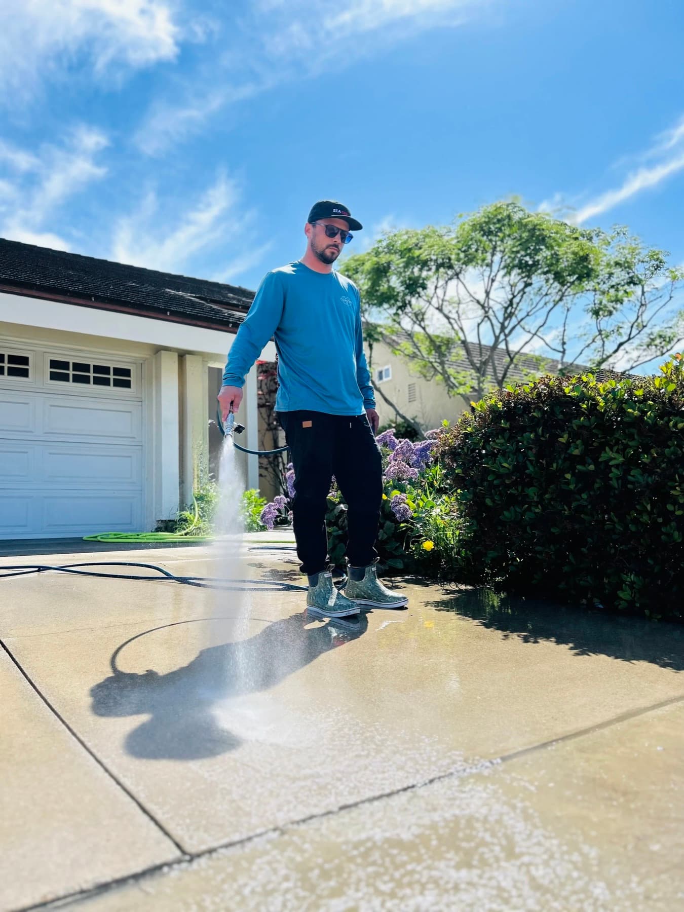 Sea Spray Pros technician washing a Huntington Beach driveway on a sunny day
