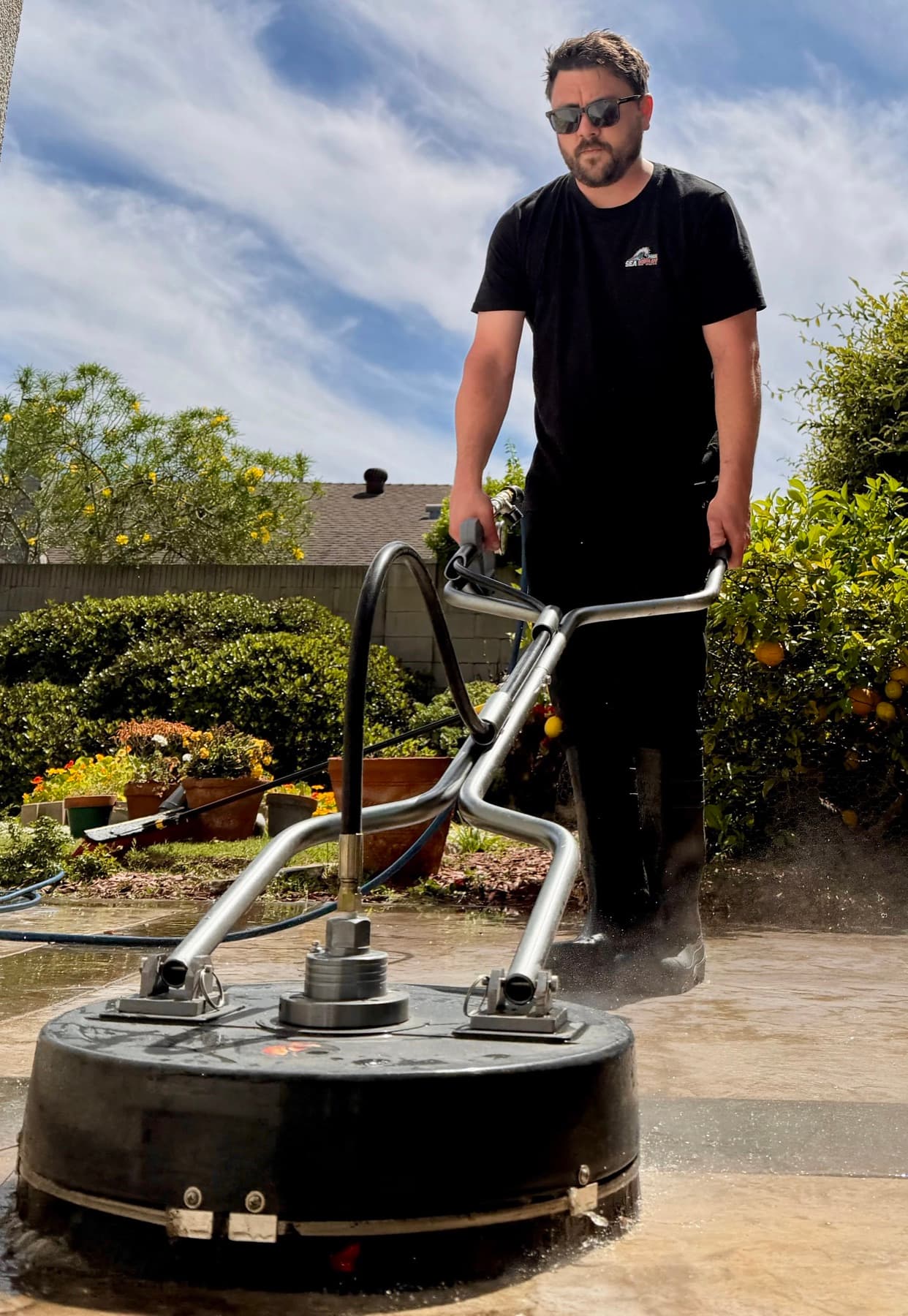 Rotary surface cleaner pressure washing a stamped concrete patio in Orange County