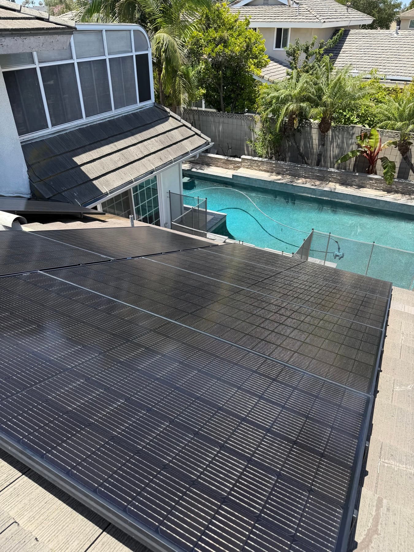 Solar panel cleaning above a backyard pool at a Huntington Beach home